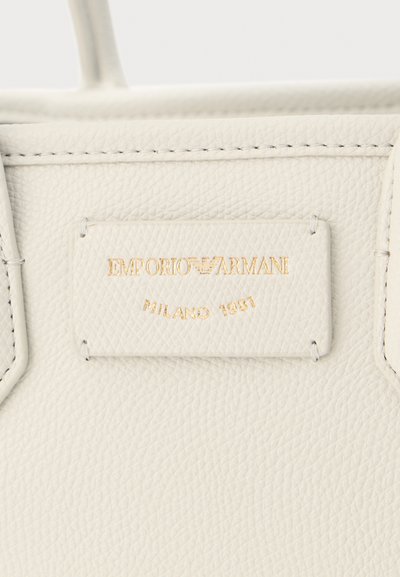 Λευκή τσάντα από δερματίνη με ανάγλυφο χρυσό λογότυπο Emporio Armani και το κείμενο «Milano 1981» σε ραμμένο ορθογώνιο πάτς.