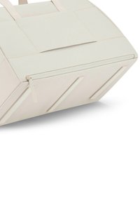 Béžová sportovní taška se strukturovaným tvarem, hladkou látkou, horním zipovým uzávěrem a texturovanými detaily po stranách. Obsahuje dvojité uši pro nošení.