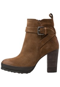 Brune ruskind ankelstøvle med en kraftig hæl, som har en dekorativ rem og spænde detaljer, rund tå og tekstureret træhæl.