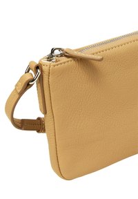 Żółta skórzana kopertówka o teksturowanej powierzchni, z zamknięciem na zamek u góry i odczepianym paskiem na nadgarstek przymocowanym z boku.