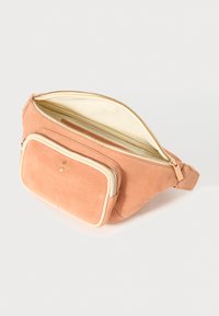 Pfirsichfarbene Wildleder-Gürteltasche mit einem cremefarbenen Reißverschluss und einer Vordertasche. Das Innere ist mit leichtem Stoff ausgekleidet.
