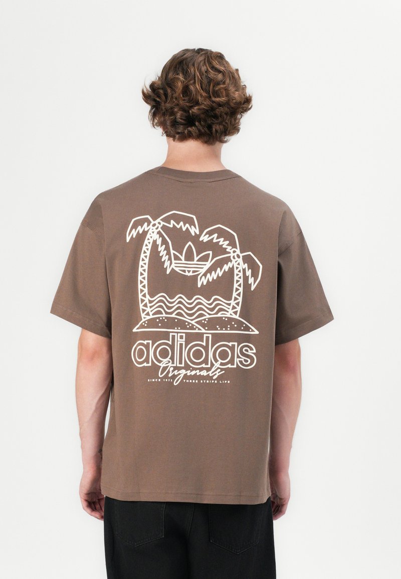 Hnědé bavlněné tričko s bílou grafikou palem a vody a nápisem "adidas Originals" na zádech. Krátké rukávy, volný střih.