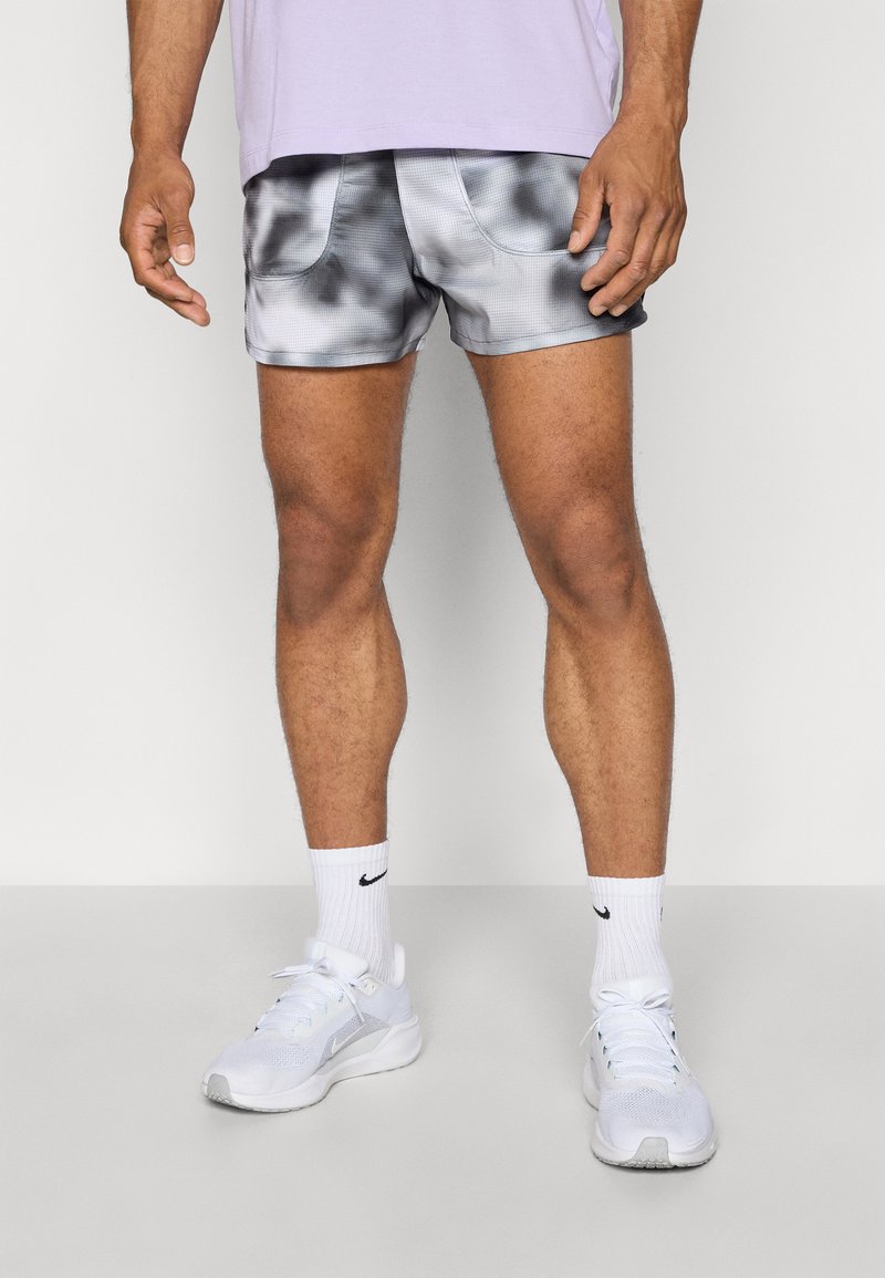 Graue und schwarze T-Shirt-Färbung Sportshorts mit zwei Vorderaschen, aus leichtem Stoff, getragen mit weißen Turnschuhen und Crew-Socken.