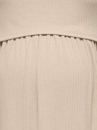 Gros plan sur un tissu beige côtelé avec des couches superposées et une couture froncée.