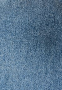 Gros plan d'un tissu denim bleu montrant une texture tissée détaillée et de légères variations de couleur.