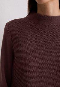Sweter pleciony w głębokim bordowym kolorze, z wysokim kołnierzem i teksturowanym wzorem, wykonany z gładkiego, miękkiego materiału.