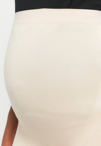 Beige tvarující spodní prádlo s hladkou, elastickou texturou. Vysoký pas, bezšvový design, vhodné pro zlepšení padnutí pod oblečením.