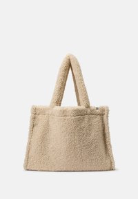 Bolsa de tela de felpa beige tipo teddy con dos asas cortas, textura suave y forma estructurada. Sin herrajes visibles ni detalles adicionales.