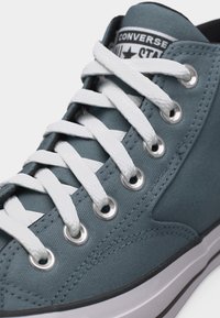 Plava Converse All Star tenisica s bijelim vezicama, metalnim otvorima za vezice i vidljivim logotipom marke na jeziku.