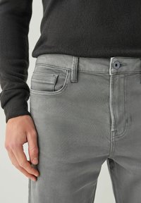 Hall lilla teksad aluspüksid, slim-fit lõikega, millel on ees nuppude sulgemine, viie tasku kujundus ja nüansilised õmblused taskute ääres.