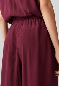 Burgunderfarbener Overall mit lockerer Passform, elastischem Taillenbund und einer Gesäßtasche. Weicher, strukturierter Stoff mit fließendem Design.