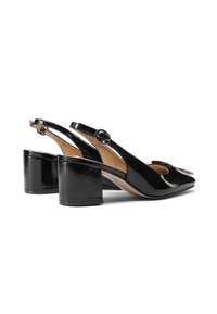 Zapatos slingback de charol negro con punta redondeada, tacón bajo y un acento de hebilla circular cerca de la correa del talón.