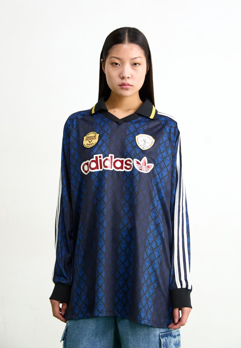 Cămașă de fotbal cu mâneci lungi, cu model albastru și negru, guler, accente galbene și logo alb Adidas, având insigne pe piept.