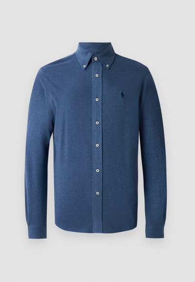 Camisa azul de manga longa com botões, feita de um tecido suave, com um colarinho estruturado e um único logótipo bordado no peito.