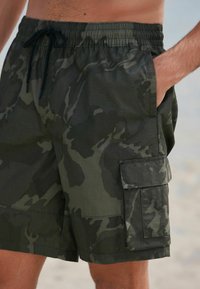 Kamo šortky na plávanie v tmavozelených odtieňoch, s elastickým pásom, šnúrkou a bočnou cargo kapsou so klopou.