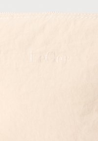 Μπεζ υφασμάτινη θήκη με ανάγλυφο λογότυπο "LeGer". Μινιμαλιστικός σχεδιασμός με απλή επιφάνεια και αντίθετη ραφή ως διακοσμητικό στοιχείο.