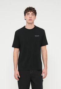 Μαύρο κοντομάνικο βαμ βακερό μπλουζάκι με στρογγυλή λαιμόκοψη. Διαθέτει μικρό γκρι λογότυπο Timberland στο στήθος.