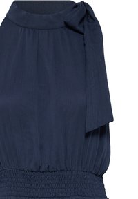 Blouse sans manches bleu marine avec encolure ronde, taille froncée et détail nœud en tissu sur l'épaule droite.