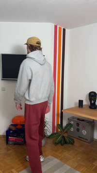 Μια τηλεόραση επίπεδης οθόνης εγκατεστημένη σε λευκό τοίχο, ένα ξύλινο τραπέζι με διακοσμητικό φυτό και πολύχρωμες κάθετες ρίγες στο φόντο.