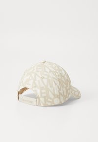 Beige szövet sapka, amelyen az egész felületet logónyomás díszíti. Ívelt karimája van, és hátul állítható pántja "Calvin Klein" felirattal van domborítva.
