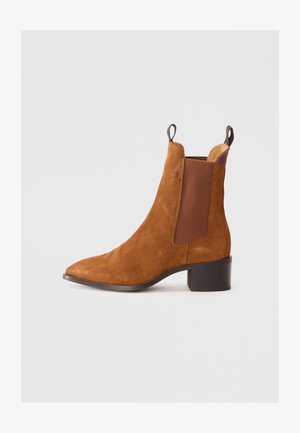 Botine din suede maro, cu panouri elastice pe laterale, vârf ascuțit și toc bloc. Include tab-uri de tragere în spate pentru o împletire ușoară.