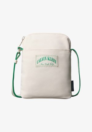 Petit sac bandoulière beige avec une sangle réglable en corde verte, une poche zippée à l'avant et un écusson logo Calvin Klein New York City.