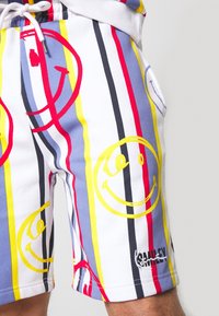 Gestreepte zwemboxers met gele, rode en blauwe lijnen en smiley-gezicht ontwerp. Gemaakt van zachte stof, met een witte elastische tailleband en trekkoord.