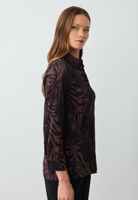Camicia button-up con texture a coste, motivo bordeaux scuro e nero, colletto classico con polsini a bottoni e vestibilità su misura.