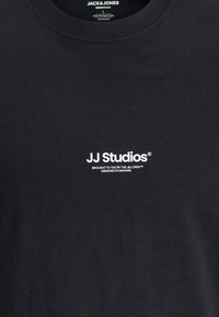 Zwarte katoenen T-shirt met een ronde hals en een wit logo waarop "JJ Studios" staat met daaronder aanvullende tekst. Klassieke pasvorm.