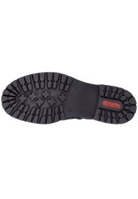 Semelle de chaussure en caoutchouc noir avec un motif de grip texturé, présentant un accent rouge avec la marque "ricker" et de profondes rainures pour une meilleure adhérence.