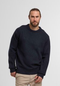 Maglione a collo rotondo di colore blu navy in maglia, con polsini e orlo a coste. Realizzato in un tessuto testurizzato, presenta una vestibilità comoda e maniche lunghe.