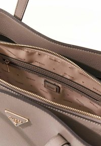 Intérieur d'un sac à main en cuir gris avec fermeture éclair dorée, doublure à motif losange et petite étiquette de marque. Dispose d'un compartiment principal spacieux.