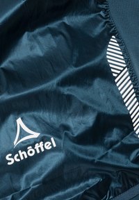 Granatowy materiał o gładkiej strukturze z białym logo "Schöffel" oraz skośnymi paskami po prawej stronie.