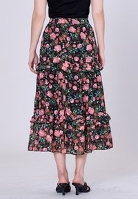 Jupe maxi florale avec une base noire, ornée de motifs de fleurs roses et vertes, de volants superposés et d'une taille confortable.