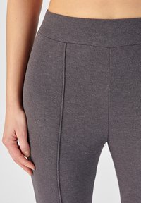 Leggings gris con relieve que cuentan con una cinturilla alta y un diseño ajustado. La textura es suave con sutiles líneas verticales y detalles de costura.