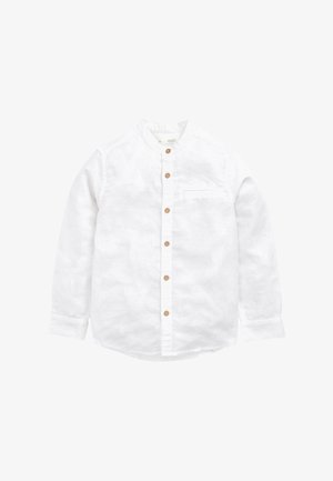 Chemise blanche à manches longues avec des boutons marron, un col mao et une petite poche poitrine sur un fond uni.