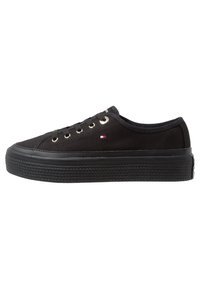 Schwarze Canvas-Sneaker mit runder Zehenpartie, flacher Gummisohle, Metallösen und Textil-Schnürsenkeln. Mit einem kleinen Logo-Patch an der Seite.