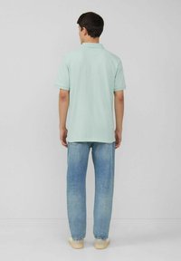 Mintgrünes Poloshirt mit kurzen Ärmeln und Kragen, kombiniert mit hellblauen gerade geschnittenen Jeans. Das Outfit zeichnet sich durch ein schlichtes Design und eine normale Passform aus.