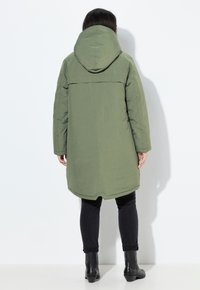 Cappotto lungo verde oliva con cappuccio, realizzato in un tessuto liscio. Presenta una lunghezza fino a metà coscia e un taglio dritto. La vista posteriore mostra dettagli minimi.
