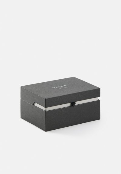 Schwarze strukturierte Box mit einem magnetischen Verschluss, ausgestattet mit einem weißen Innenraum und einem minimal geprägten Logo auf der Oberseite. Die Maße sind kompakt und rechteckig.