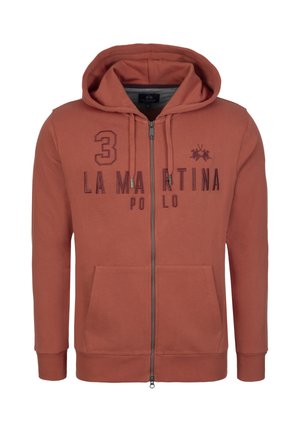 Rust-colored zip-up hoodie, made of soft fabric. Features a kangaroo pocket, drawstring hood, and printed branding on the front.