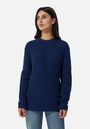 Dunkelblauer Strickpullover mit einem strukturierten Muster, langen Ärmeln und einem runden Ausschnitt, kombiniert mit hellen Jeans.