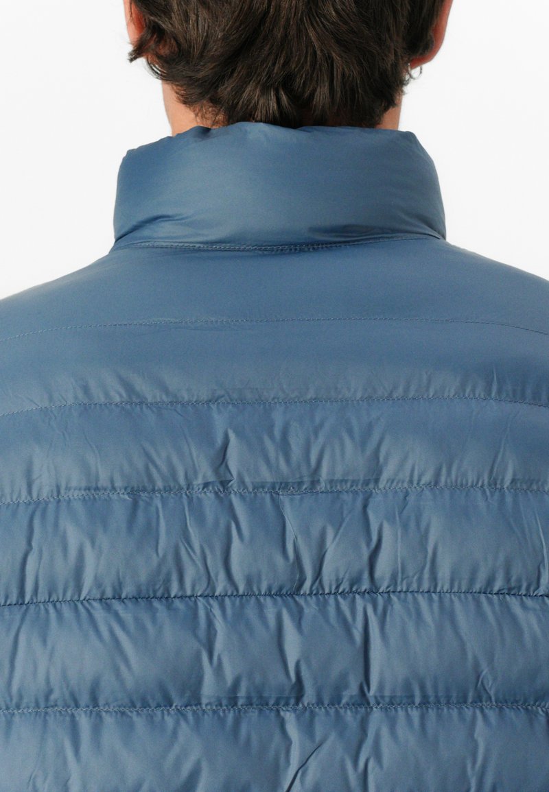 Chaqueta hinchada azul con un alto cuello, que presenta un diseño acolchado y una textura suave. Los detalles de costura visibles realzan la estructura.