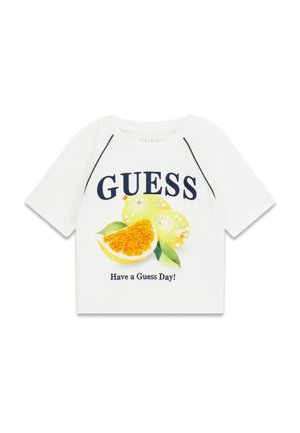Chemise blanche à manches courtes avec "GUESS" en grosses lettres, un visuel de fruit agrume avec des paillettes, et le texte "Have a Guess Day !" en dessous.