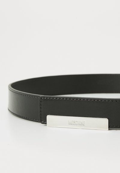 Svart läderbälte med en slät yta, som har en silverfärgad rektangulär spänne graverad med "Moschino." Enkelt, minimalistiskt design.