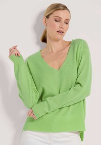V-Ausschnitt, langärmeliger Pullover aus hellgrünem Strickstoff mit gerippten Bündchen und Saum, mit seitlichen Schlitzen am unteren Ende für zusätzlichen Stil.