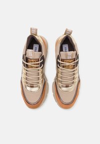 Beige Sneaker mit Mesh- und Wildledertexturen, goldenen Akzenten und braunen Gummisohlen. Mit Schnürsenkeln und einem Ziehschlaufe an der Zunge.
