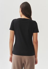 Zwart T-shirt met korte mouwen en een ronde hals, gemaakt van zachte katoen, met een nauwsluitend design, een gladde textuur en een minimalistische stijl.