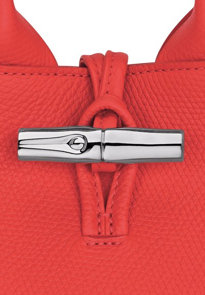 Red textured leather bag with a silver polished metal clasp featuring a toggle and loop closure.