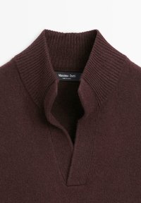 Bordowy sweter dziany z prążkowanym wysokim kołnierzem i delikatnym dekoltem w kształcie litery V. Charakteryzuje się miękką fakturą, starannym wykończeniem i metką marki.